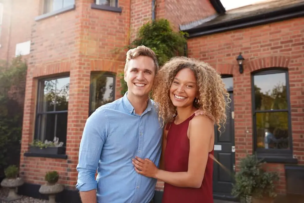 couple stands in front of new home after winning bidding war