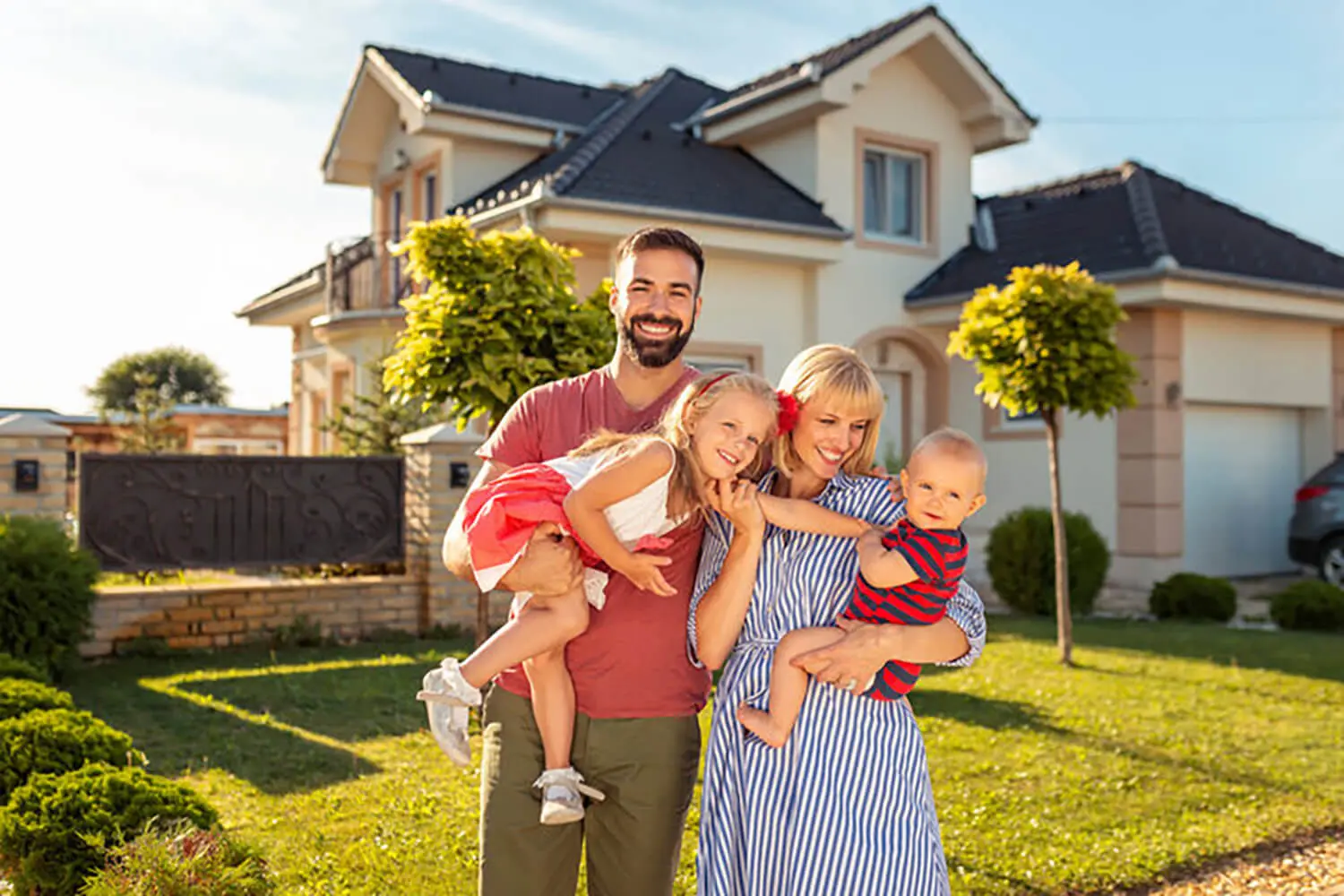 Happy second-time home buyers standing in front of their new house, showing what second-time buyers underestimate when buying again